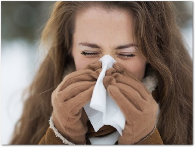 Young woman blowing nose in winter outdoors