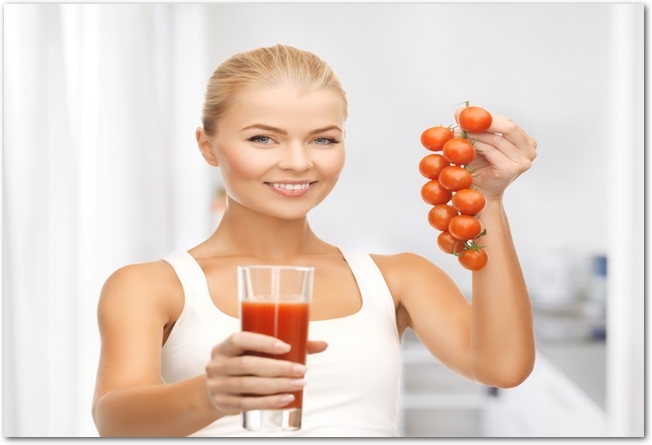 woman holding glass of juice and tomatoes