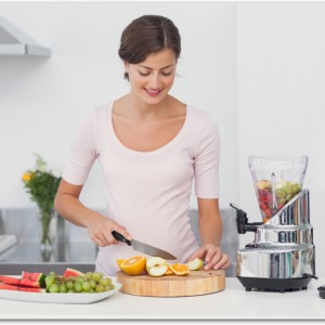 Pregnant woman cutting fruits in the kitchen to make a fruit cocktail
